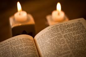 Åpen bibel foran tente lys